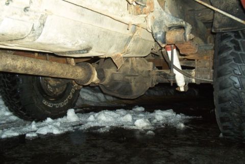 1991 Ford F-250 - A close-up shot reveals the rear axle and suspension components of a truck, with snow and ice visible on the ground below.