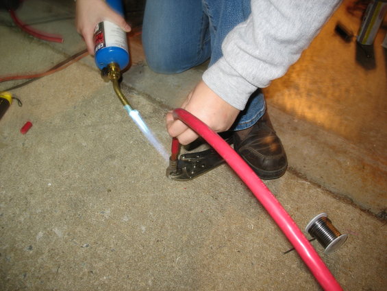 Person using a propane torch to crimp a red cable connector