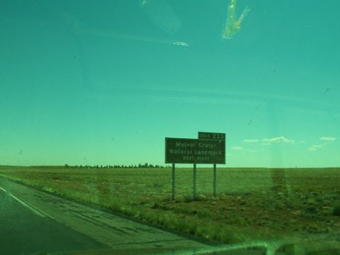1995 Ford C-350 (Centurion Conversions) - A sign points the way to Meteor Crater, a natural landmark, off the highway.