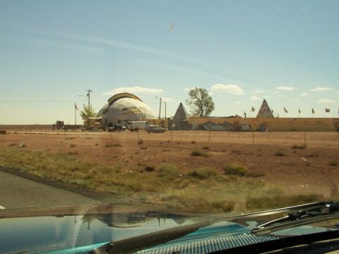 1995 Ford C-350 (Centurion Conversions) - A collection of vehicles are parked in front of a large dome-shaped building in a desert environment.
