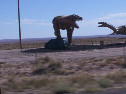 1995 Ford C-350 (Centurion Conversions) - Dinosaur statues are visible along a roadside in a barren landscape.
