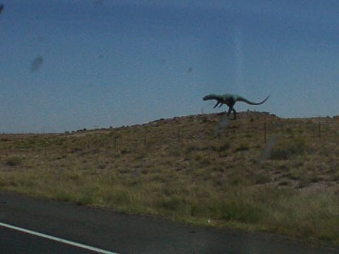1995 Ford C-350 (Centurion Conversions) - A dinosaur statue stands on a hill overlooking a road.