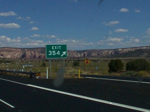1995 Ford C-350 (Centurion Conversions) - A highway exit sign indicates exit 354, with a vast landscape of mesas under a cloudy sky.