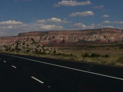 1995 Ford C-350 (Centurion Conversions) - Driving through a scenic desert landscape with a highway in the foreground and mesas in the distance.