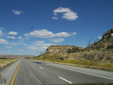 1995 Ford C-350 (Centurion Conversions) - A white truck travels down a highway through a scenic landscape with rocky hills and scattered clouds.