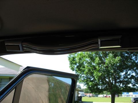 1995 Ford C-350 (Centurion Conversions) - Interior shot showing a grab handle above the door frame, with a view of trees and buildings outside.