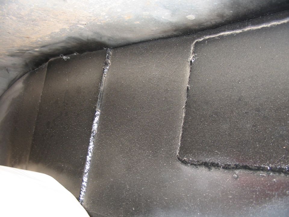 Undercarriage of a vehicle showing welded seams and textured black coating