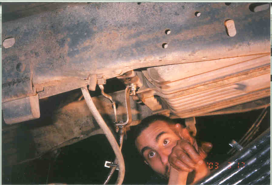 Underbody view of a truck's suspension and fuel tank with a person looking up