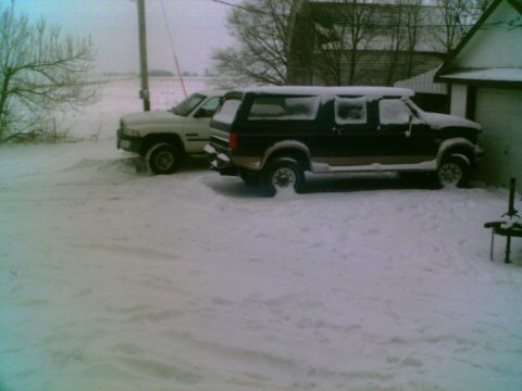 1995 Ford C-350 (Centurion Conversions) - Two trucks are parked in a snowy yard beside a building and a utility pole.