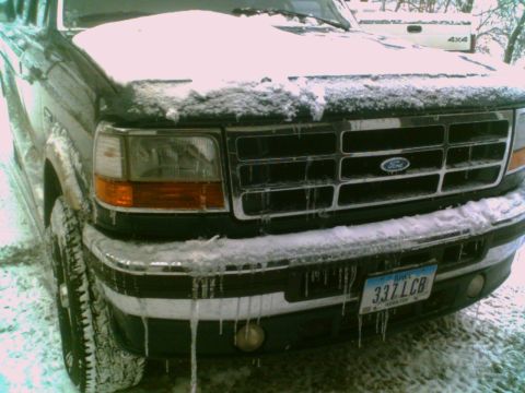1995 Ford C-350 (Centurion Conversions) - A Ford truck's front end is covered in snow and icicles, with a license plate visible.