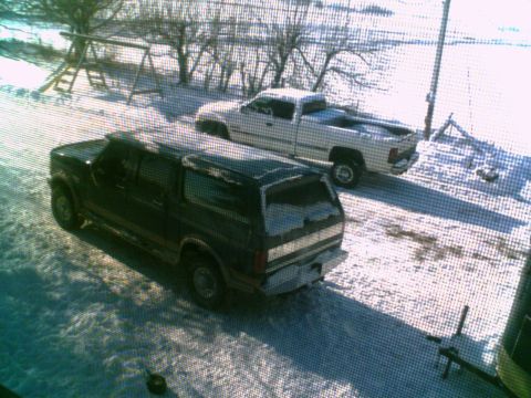 1995 Ford C-350 (Centurion Conversions) - Two vehicles, a dark SUV and a white pickup, sit in a snow-covered yard.