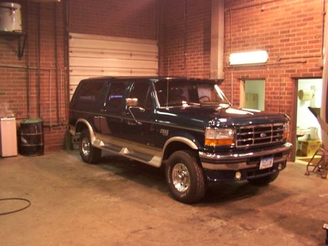 1995 Ford C-350 (Centurion Conversions) - This Ford Bronco SUV is parked indoors in a garage with brick walls and a large overhead door.