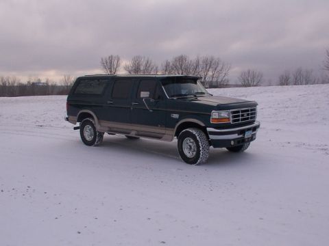 1995 Ford C-350 (Centurion Conversions) - Dark green 1995 Ford C-350 (Centurion Conversions) SUV sits in a snow-covered landscape under an overcast sky.