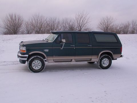 1995 Ford C-350 (Centurion Conversions) - A dark green Ford SUV conversion with tan lower body trim sits in a snowy landscape under an overcast sky.