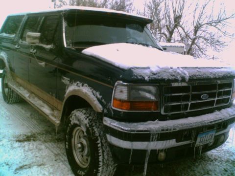 1995 Ford C-350 (Centurion Conversions) - Snow-covered Ford Bronco in a winter setting. The vehicle's front end and side profile are partially obscured by snow.