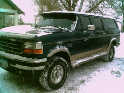 1995 Ford C-350 (Centurion Conversions) - This 1995 Ford C-350 (Centurion Conversions) is seen covered in snow, highlighting its dark green exterior with tan trim.