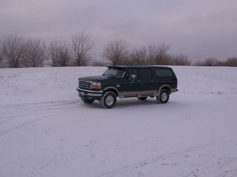 1995 Ford C-350 (Centurion Conversions) - Dark green 1995 Ford Bronco SUV sits in a snow-covered landscape under an overcast sky.