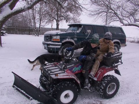 1995 Ford C-350 (Centurion Conversions) - Children on an ATV in the snow with a green Ford truck behind them.