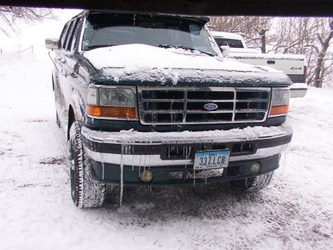 1995 Ford C-350 (Centurion Conversions) - A snow-covered Ford truck sits outside in winter conditions, with icicles hanging from its bumper.