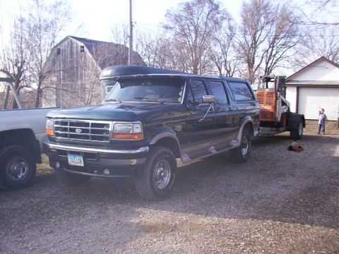 1995 Ford C-350 (Centurion Conversions) - A 1995 Ford C-350 Centurion Conversions SUV is parked next to a pickup truck and towing a Bobcat loader.