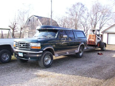 1995 Ford C-350 (Centurion Conversions) - 1995 Ford C-350 Centurion Conversion van is parked next to another truck and towing a Bobcat skid steer loader.