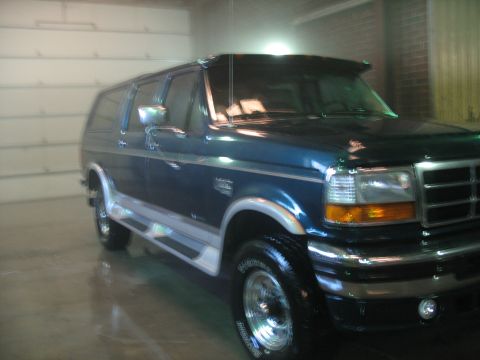 1995 Ford C-350 (Centurion Conversions) - This dark blue SUV has chrome accents and running boards, viewed from the front three-quarter angle.