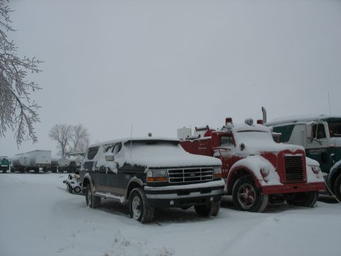 1995 Ford C-350 (Centurion Conversions) - Several vehicles, including a Ford Bronco and two trucks, are covered in snow.