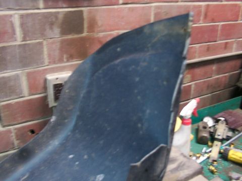 1995 Ford C-350 (Centurion Conversions) - A dark blue curved panel is shown in close-up, resting against a brick wall in a workshop setting.