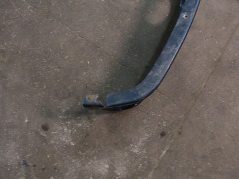 1995 Ford C-350 (Centurion Conversions) - A close-up view of a damaged blue metal automotive part resting on a concrete surface.