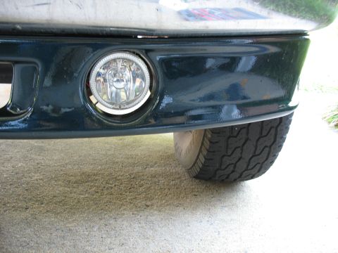 1995 Ford C-350 (Centurion Conversions) - Close-up of a dark green front bumper, showing a fog light and part of a tire.
