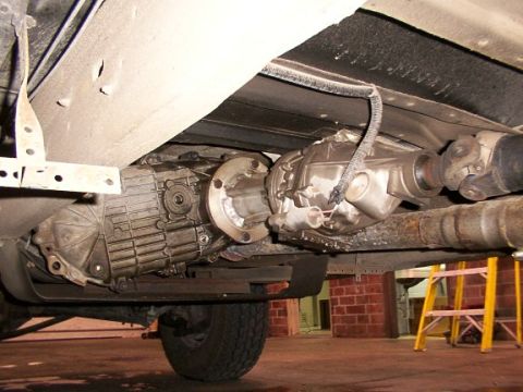 1995 Ford C-350 (Centurion Conversions) - Close-up of the drivetrain components, including the transmission and driveshaft, under a vehicle.