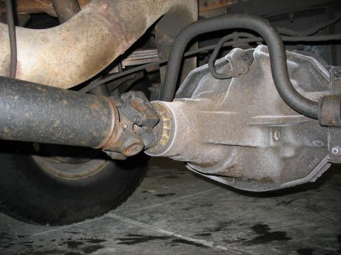 1995 Ford C-350 (Centurion Conversions) - Close-up view of the rear axle, driveshaft, and differential housing on a vehicle.