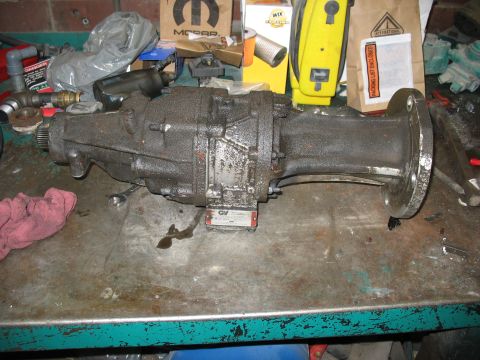 1995 Ford C-350 (Centurion Conversions) - A transmission part, possibly from a truck, sits on a cluttered workbench.