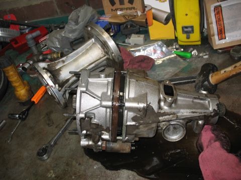 1995 Ford C-350 (Centurion Conversions) - A vehicle's transmission or transfer case is disassembled on a floor, surrounded by tools and shop rags.