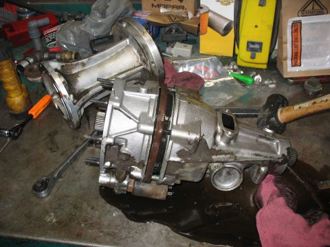1995 Ford C-350 (Centurion Conversions) - A disassembled transmission part sits on a workbench with tools and oil spilled around it.