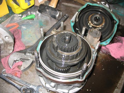 1995 Ford C-350 (Centurion Conversions) - Close-up of a disassembled transmission part, showing internal gears and components on a cluttered workbench.
