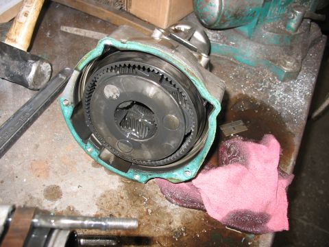 1995 Ford C-350 (Centurion Conversions) - Close-up of a disassembled transmission part, showing internal gears and a workbench setting.