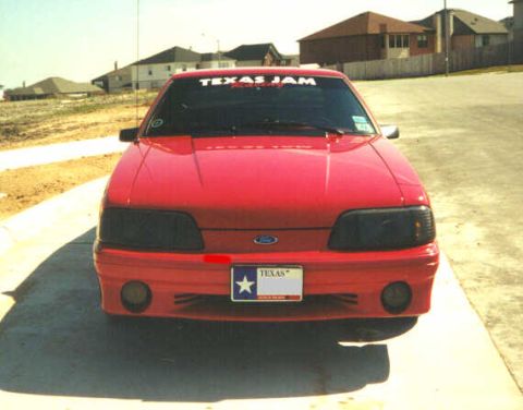 1992 Ford Mustang - A red 1992 Ford Mustang is shown from the front, a 'TEXAS JAM' banner on the windshield and a Texas license plate.