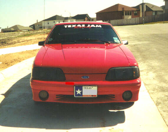 Red 1992 Ford Mustang front view with Texas license plate and 'TEXAS JAM' banner on windshield