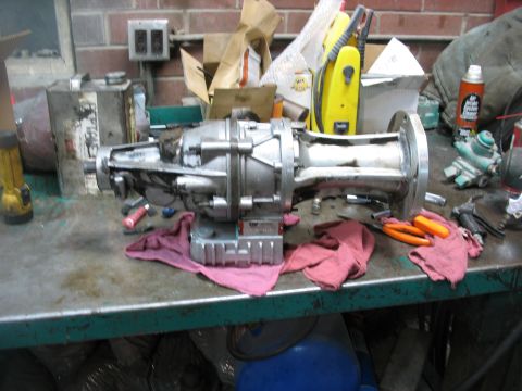 1995 Ford C-350 (Centurion Conversions) - Workbench with a disassembled transmission part, tools, and rags.