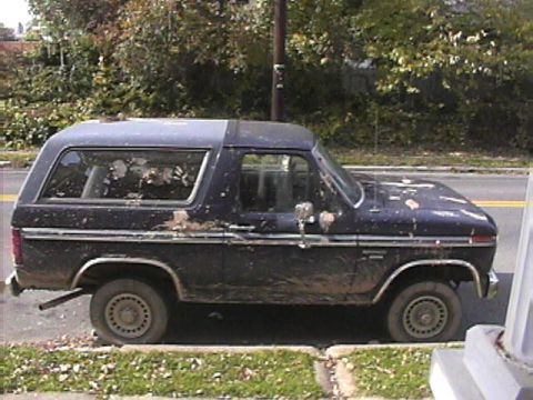 1985 Ford Bronco - This 1985 Ford Bronco, seen from the side, appears to have a two-tone paint job with a darker upper section and a lighter lower section.