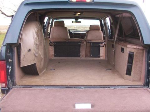 1995 Ford C-350 (Centurion Conversions) - The rear interior of a van is visible, a spare tire, seating, and a carpeted cargo space.