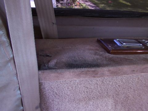 1995 Ford C-350 (Centurion Conversions) - Close-up of the interior, highlighting a seatbelt and a decorative panel with a latch mechanism.