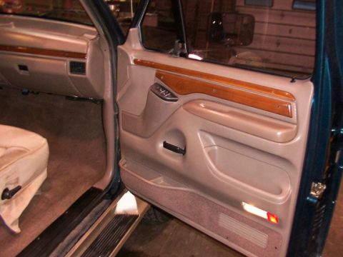 1995 Ford C-350 (Centurion Conversions) - Close-up of a vehicle's interior door panel and part of the seat, showing wood accents and controls.