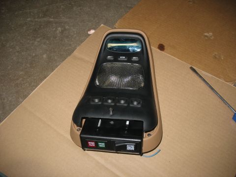 1995 Ford C-350 (Centurion Conversions) - A vehicle's overhead console, removed from its original location, sits on a cardboard surface next to a screwdriver.