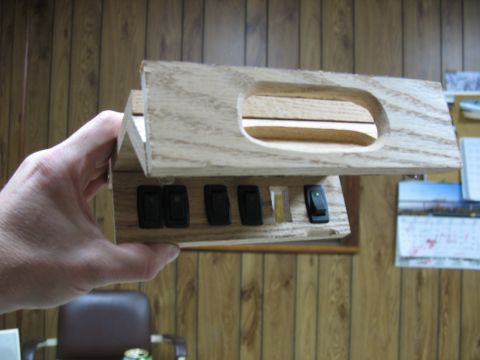 1995 Ford C-350 (Centurion Conversions) - A wooden overhead console with several black switches is held by a hand.