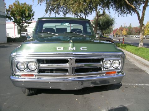 1996 Ford Bronco - Front view of a green GMC truck with a prominent chrome grille and dual headlights.