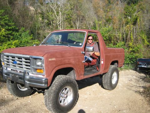 1989 Ford Bronco - This lifted Ford Bronco is being driven off-road, with a second vehicle following behind.