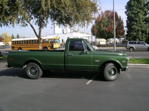1996 Ford Bronco - Side view of a green pickup truck, with a school bus and SUV in the background.