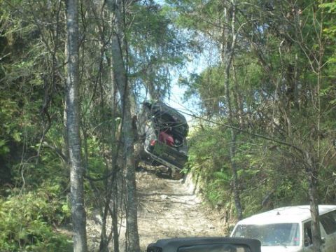 1989 Ford Bronco - Off-road vehicles tackle a challenging dirt trail through a dense forest. Multiple vehicles are present on the scene.